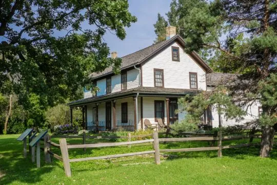 Gibbs Farm, via RCHS. it is a white two story farmhouse with a gray roof and gray trimmed windows.