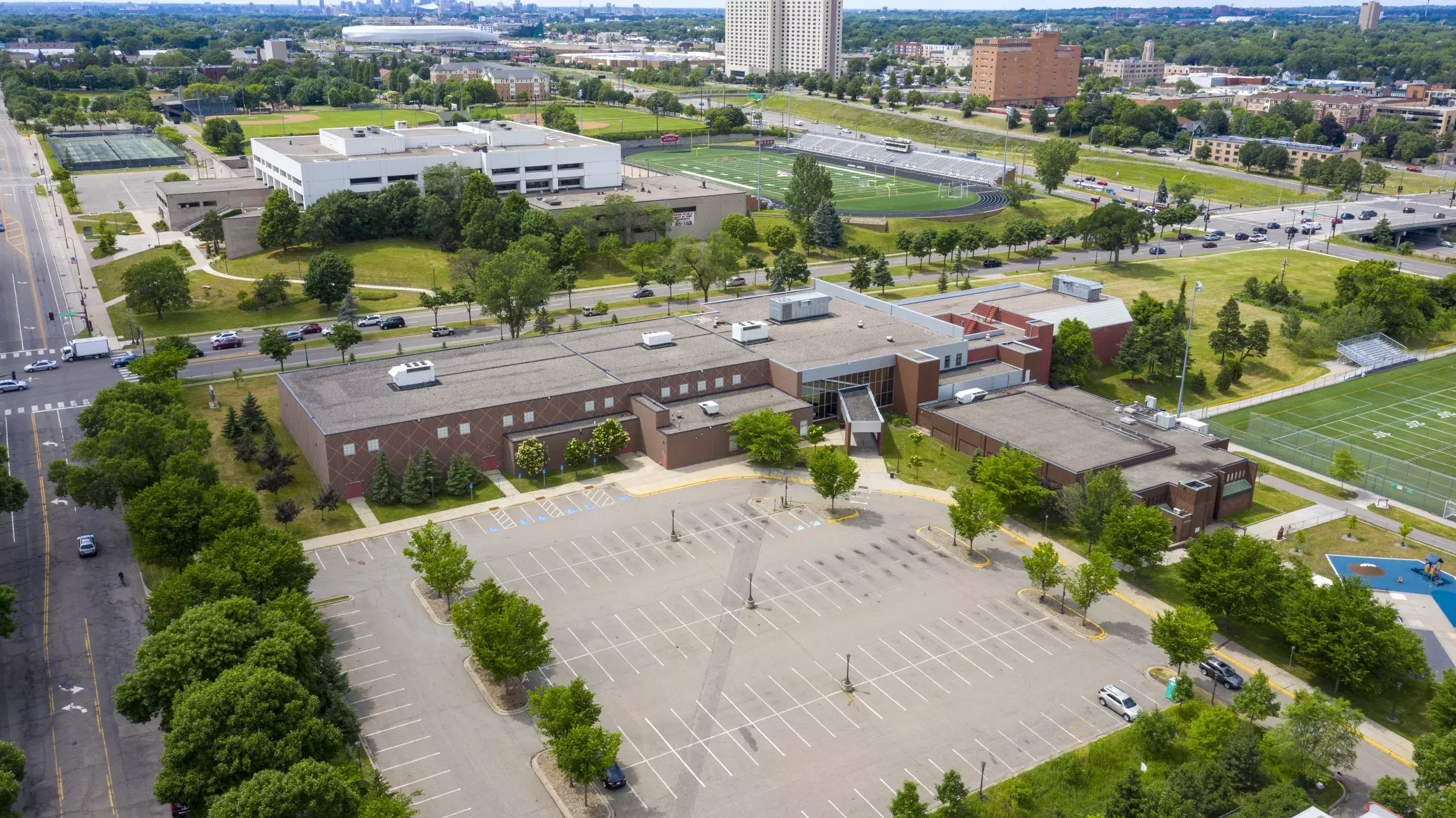 An aerial view of the Oxford Recreation Center. It is a sprawling brick complex with a football field and large parking lot, plus playground. You can see where the original jimmy lee rec center connects to the new building.