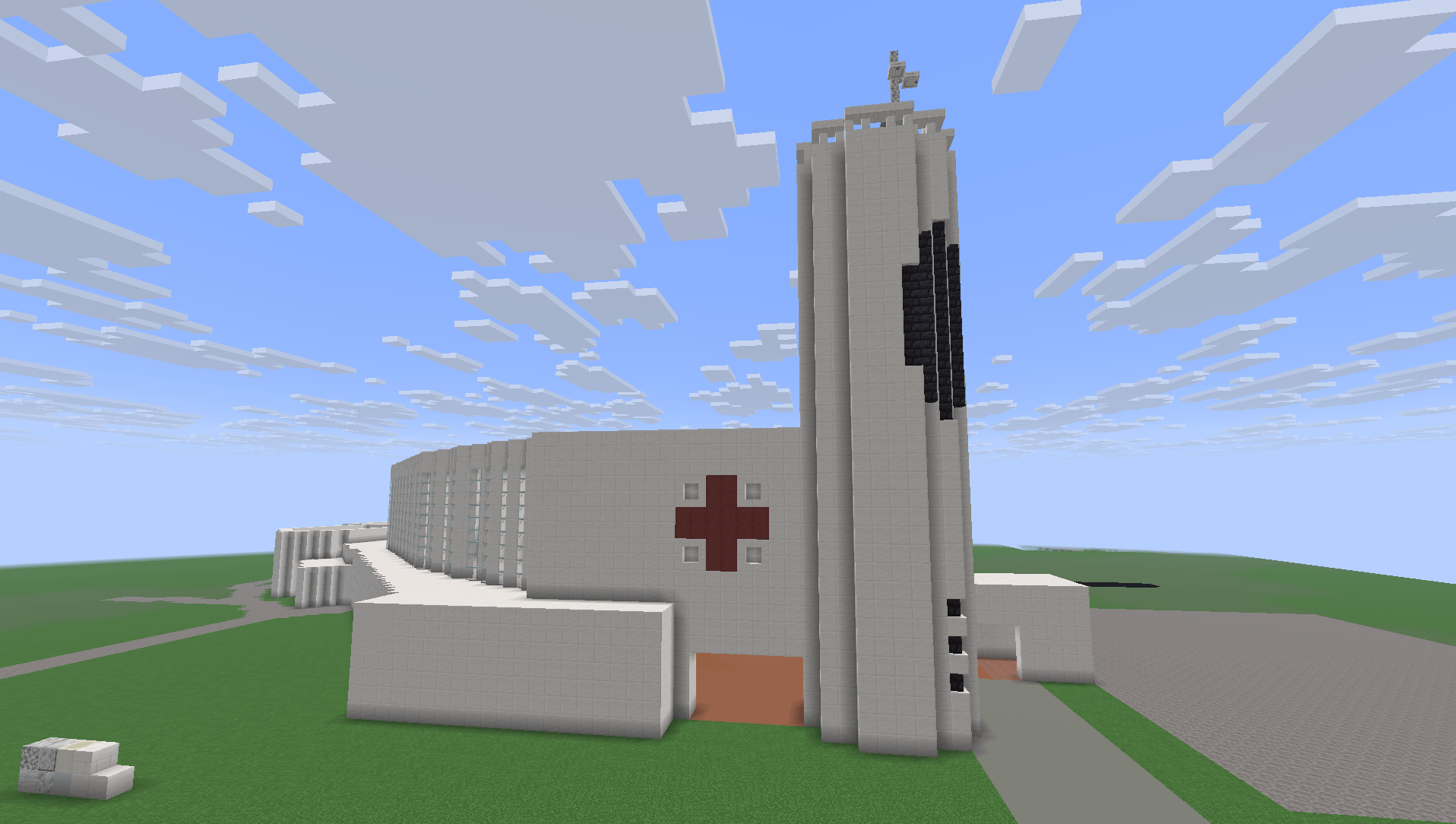 A screenshot of St Columba Catholic Church, viewed from Thomas Ave. It is a modernist chuch made of white stone, with an oval shape and tall belltower. It has a red cross on the main body, and a gray cross on the tower.